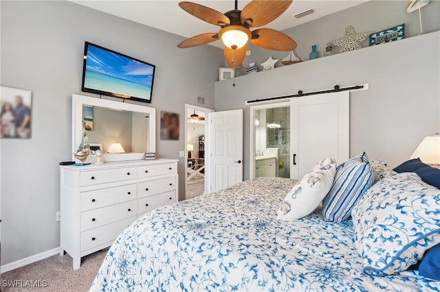 carpeted bedroom with ensuite bathroom, a towering ceiling, a barn door, and ceiling fan