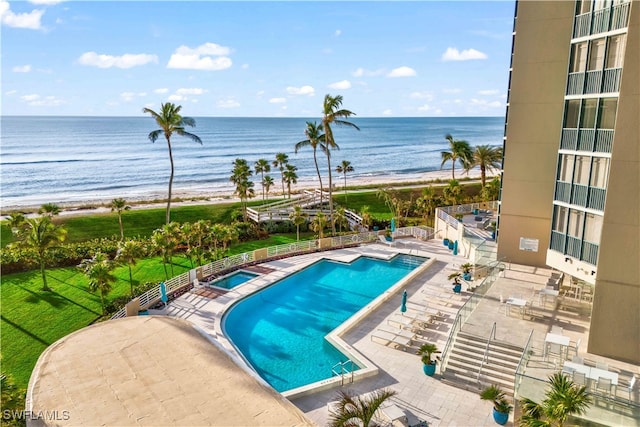 view of pool featuring a patio, a water view, and a beach view