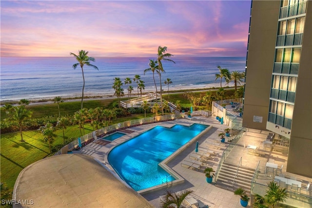 pool at dusk with a patio and a water view