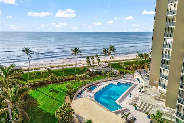 view of swimming pool featuring a patio, a water view, and a view of the beach