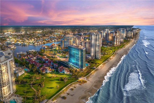 aerial view at dusk featuring a beach view and a water view