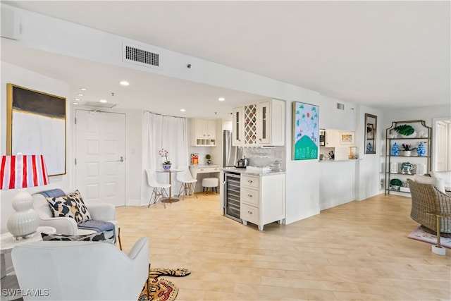 living room with wine cooler, bar, and light hardwood / wood-style flooring