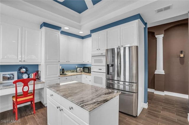 kitchen featuring wood tiled floor, stainless steel fridge, visible vents, and ornate columns