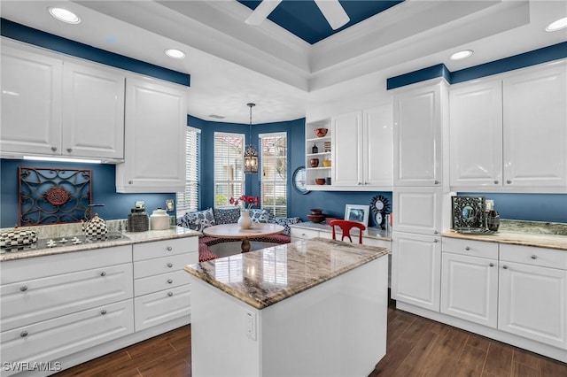 kitchen featuring light stone counters, electric stovetop, dark wood-type flooring, white cabinetry, and a raised ceiling