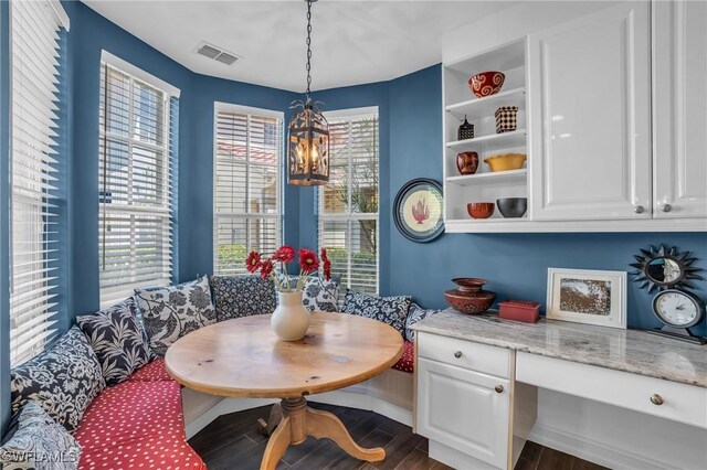 dining area with breakfast area, dark wood finished floors, visible vents, and a notable chandelier