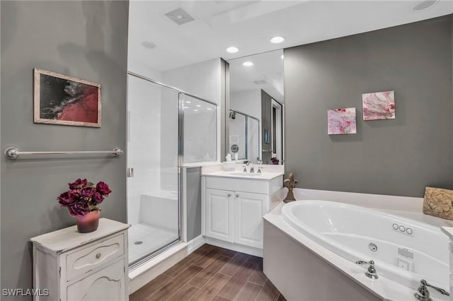 bathroom with a whirlpool tub, a stall shower, vanity, and wood finish floors