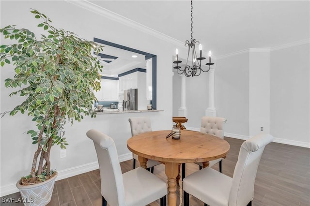 dining room with crown molding, a notable chandelier, ornate columns, wood finished floors, and baseboards