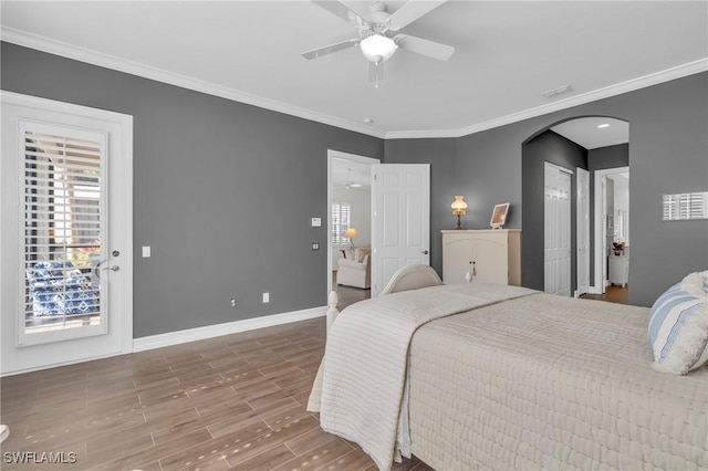 bedroom featuring arched walkways, crown molding, visible vents, wood finished floors, and baseboards