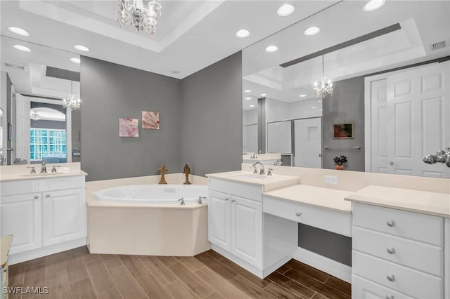 full bath with wood tiled floor, a raised ceiling, a notable chandelier, and a sink