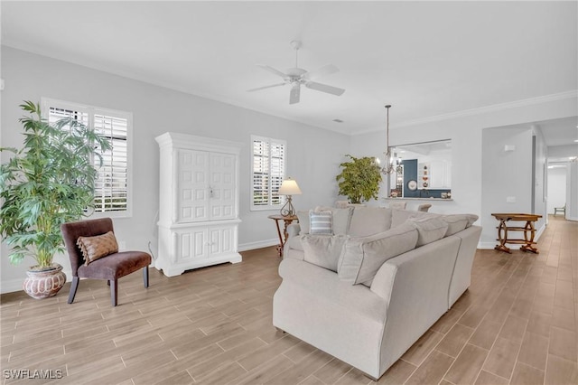 living area with ornamental molding, wood finish floors, baseboards, and ceiling fan with notable chandelier