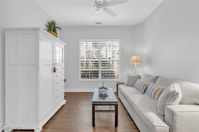 living room featuring a ceiling fan, visible vents, baseboards, and wood finished floors