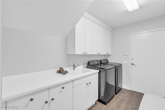 laundry room featuring washing machine and dryer, cabinet space, a sink, and wood tiled floor