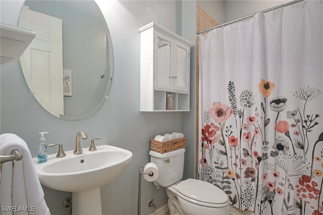 bathroom with toilet, curtained shower, and sink