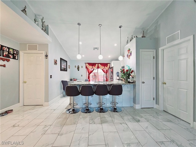 kitchen with a breakfast bar, light stone counters, kitchen peninsula, white cabinets, and pendant lighting