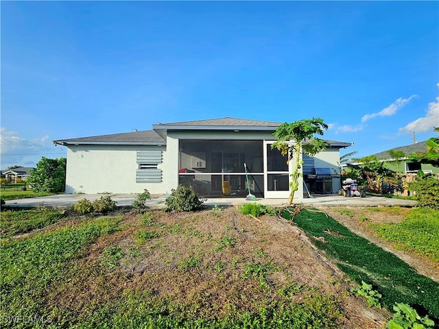 rear view of house featuring a sunroom and a patio area