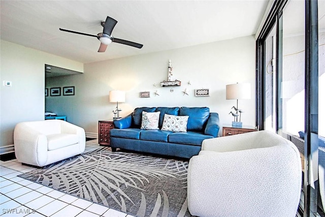 living area with ceiling fan, baseboards, and tile patterned floors