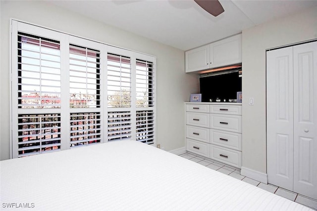 unfurnished bedroom featuring a ceiling fan, baseboards, a closet, and light tile patterned flooring