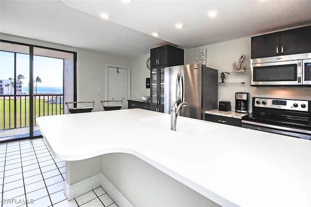 kitchen featuring recessed lighting, light countertops, appliances with stainless steel finishes, light tile patterned flooring, and a sink