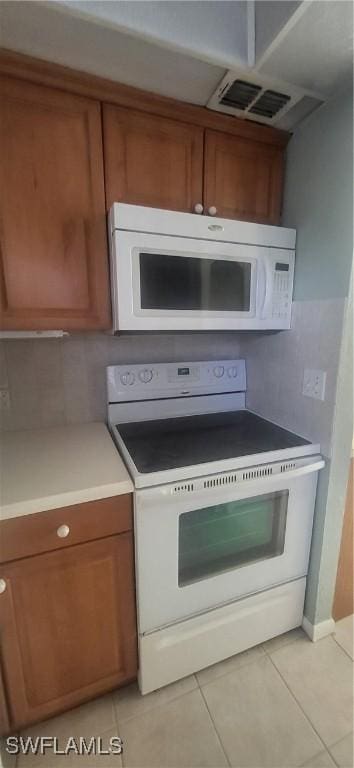 kitchen featuring light tile patterned floors, backsplash, and white appliances