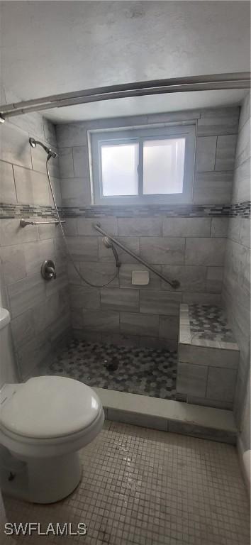 bathroom with tiled shower, a wealth of natural light, tile patterned floors, and toilet