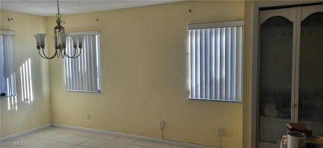 empty room featuring light tile patterned flooring and a chandelier