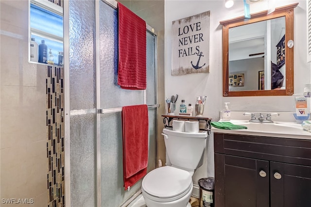 bathroom featuring toilet, vanity, and a shower with shower door