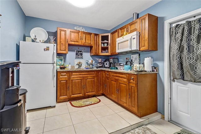 kitchen featuring light stone counters, light tile patterned floors, white appliances, and sink