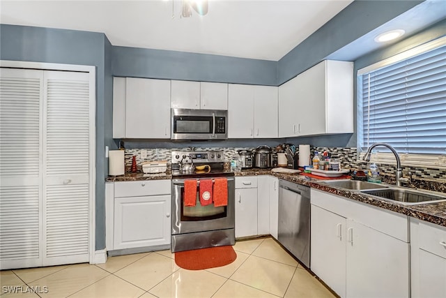 kitchen with decorative backsplash, sink, light tile patterned flooring, white cabinetry, and appliances with stainless steel finishes