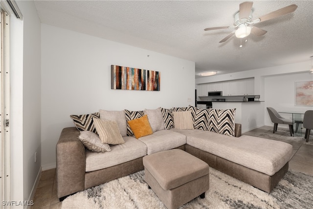 living room with a textured ceiling, ceiling fan, and light tile patterned flooring