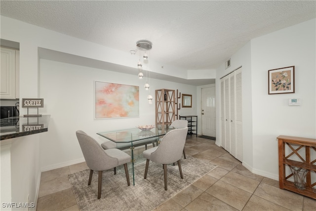 tiled dining room featuring a textured ceiling