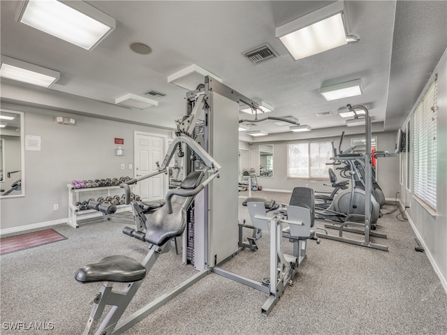 exercise room with a textured ceiling and light colored carpet