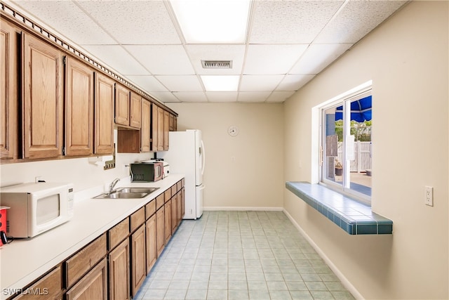 kitchen featuring a paneled ceiling, white appliances, and sink