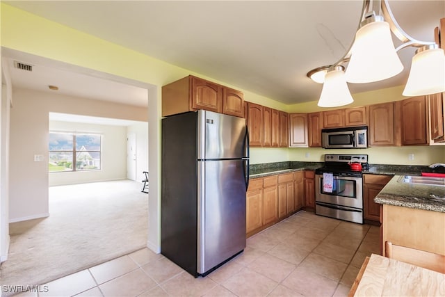 kitchen featuring sink, hanging light fixtures, dark stone counters, light colored carpet, and appliances with stainless steel finishes