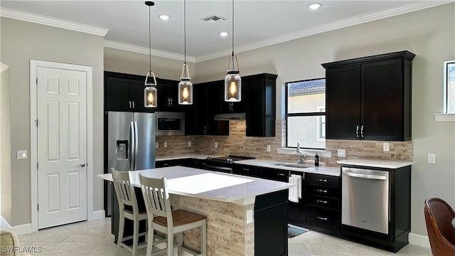 kitchen with appliances with stainless steel finishes, decorative light fixtures, a center island, light countertops, and a sink