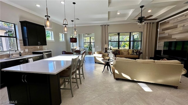 kitchen with a sink, a kitchen island, open floor plan, light countertops, and decorative light fixtures