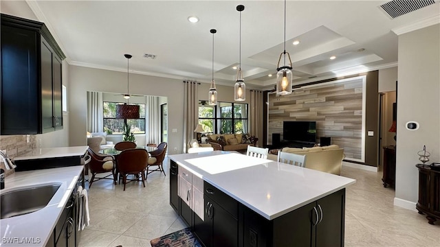 kitchen with an accent wall, a center island, hanging light fixtures, light countertops, and dark cabinetry