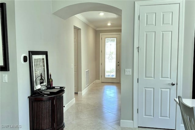 interior space featuring baseboards, visible vents, arched walkways, and ornamental molding