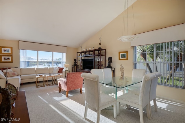 carpeted dining space with high vaulted ceiling