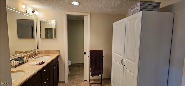 bathroom featuring a textured ceiling, vanity, and toilet