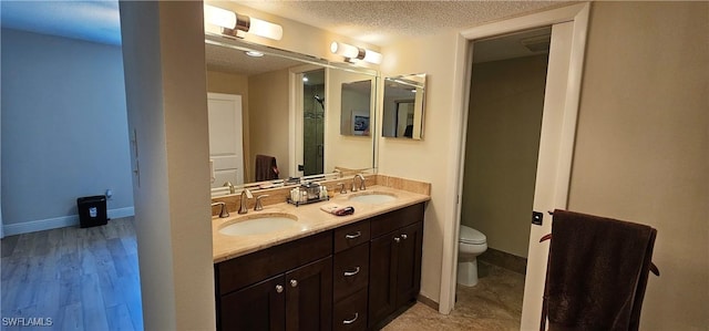 bathroom with hardwood / wood-style floors, vanity, toilet, and a textured ceiling