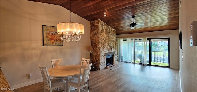 dining room featuring high vaulted ceiling, ceiling fan with notable chandelier, a stone fireplace, hardwood / wood-style flooring, and wood ceiling