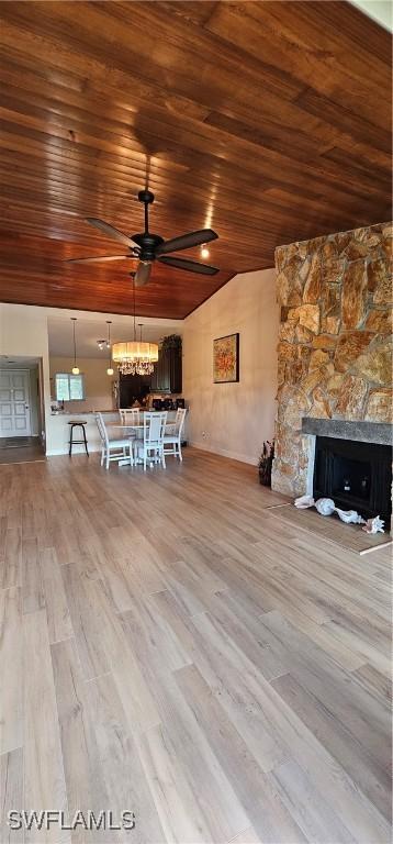 unfurnished living room with a stone fireplace, ceiling fan, wooden ceiling, and light wood-type flooring