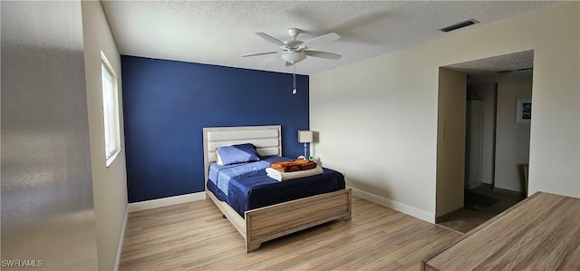 bedroom featuring ceiling fan, light hardwood / wood-style flooring, and a textured ceiling