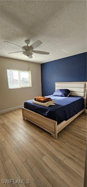 unfurnished bedroom with ceiling fan, a textured ceiling, and light wood-type flooring