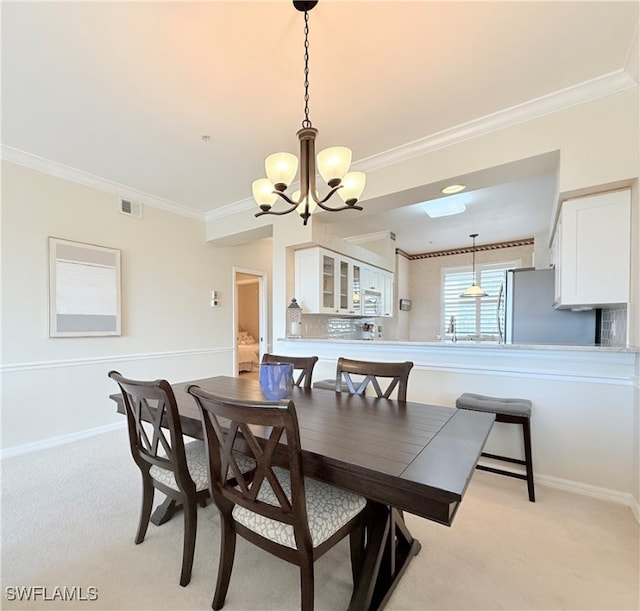 carpeted dining area featuring an inviting chandelier and ornamental molding