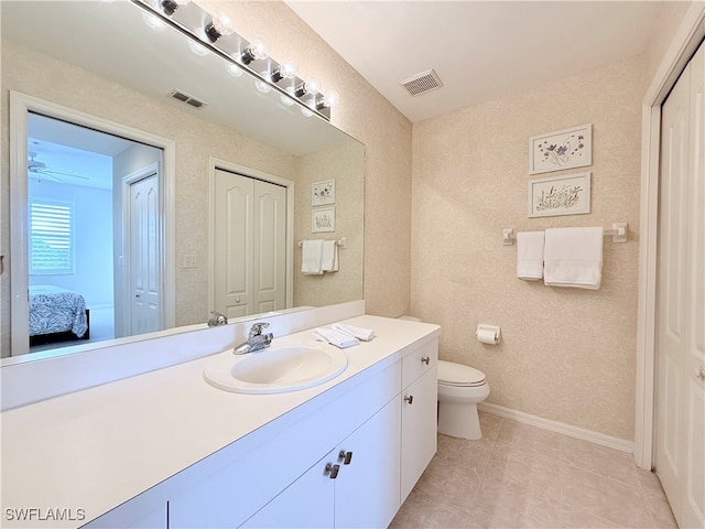 bathroom with toilet, vanity, and tile patterned floors