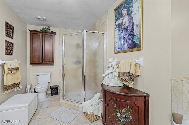 bathroom featuring tile patterned floors, toilet, a shower with door, and a textured ceiling