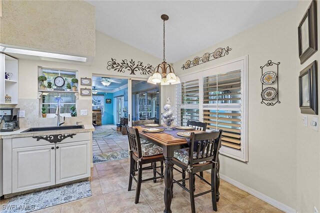 tiled dining area with ceiling fan with notable chandelier, sink, and vaulted ceiling