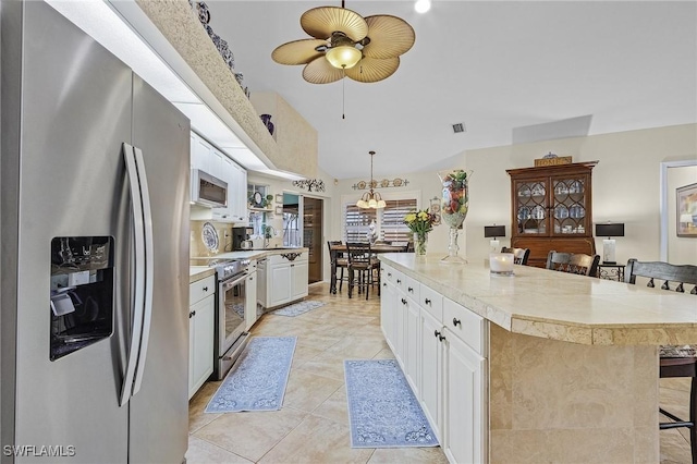 kitchen featuring white cabinets, pendant lighting, a breakfast bar area, a kitchen island, and appliances with stainless steel finishes