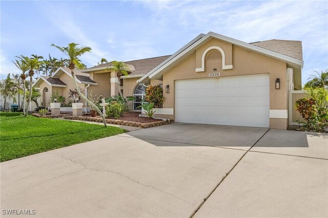 view of front facade with an attached garage, driveway, a front yard, and stucco siding